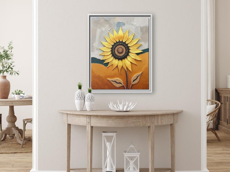 Puede incluir: Una obra de arte enmarcada que presenta un gran girasol amarillo con un centro marr&oacute;n oscuro. La pintura tiene una apariencia texturizada, con un fondo de tonos naranja, azul y gris. La obra de arte se exhibe sobre una consola de madera.