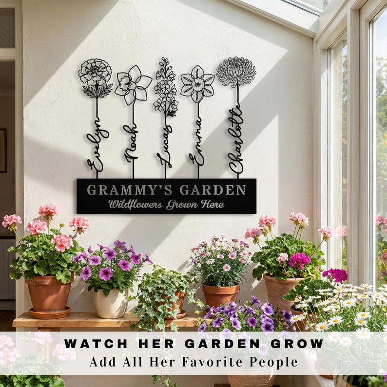 K&ouml;nnte beinhalten: Schwarzes Metall-Gartenschild mit f&uuml;nf stilisierten Blumenstielen, jeweils mit einem Namen: Evelyn, Noah, Lucas, Emma und Charlotte. Das Schild tr&auml;gt die Aufschrift "Grammy's Garden" und "Wildflowers Grown Here". Darunter steht "Watch Her Garden Grow, Add All Her Favorite People."
