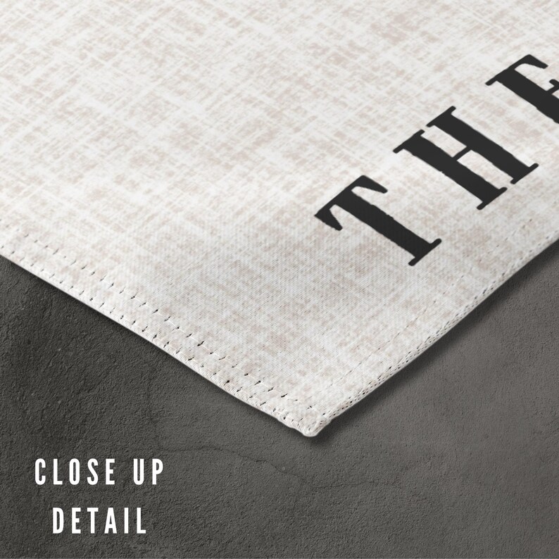 May include: Close-up of a white fabric with the word "THE" printed in black.