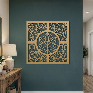 May include: A square wooden wall art piece with a floral design. The artwork features a central circular motif surrounded by a square frame, all cut from light-coloured wood. The design includes stylised flowers and leaves, creating a decorative element.