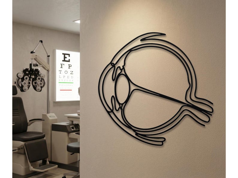 Minimalist black metal eyeball sculpture mounted in an optometry exam room next to vision testing equipment.