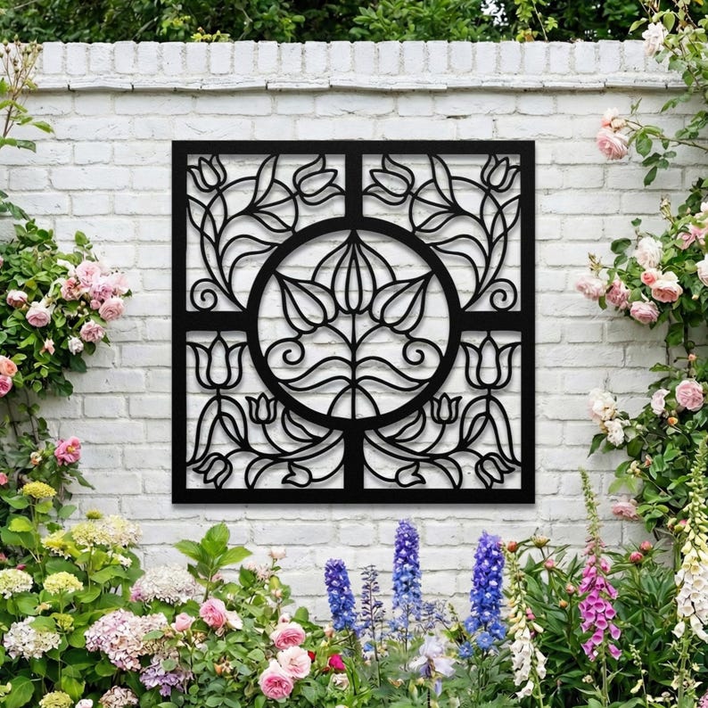 Black metal garden wall grille on white brick fence, outdoor architectural art.