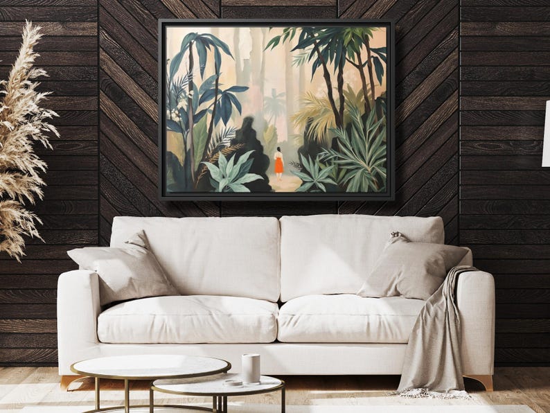 Puede incluir: Una impresi&oacute;n art&iacute;stica enmarcada que representa una exuberante escena de selva tropical con una persona con un vestido naranja caminando por un sendero. La obra de arte presenta varios tonos de verde y marr&oacute;n, con un marco negro.