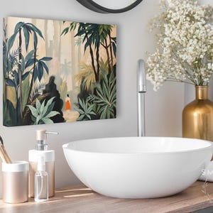 Puede incluir: Un lienzo que representa una exuberante escena de la jungla con palmeras y una figura con un vestido naranja. El ba&ntilde;o cuenta con un lavabo blanco, detalles dorados y un portacepillos.