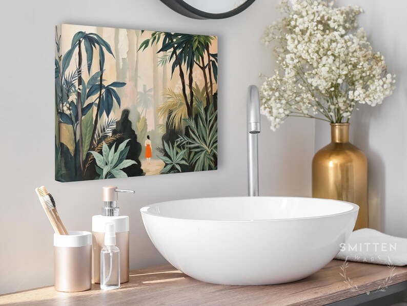 Puede incluir: Un lienzo que representa una exuberante escena de la jungla con palmeras y una figura con un vestido naranja. El ba&ntilde;o cuenta con un lavabo blanco, detalles dorados y un portacepillos.