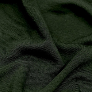 Puede incluir: Una tela de color verde bosque oscuro con una textura de punto visible y pliegues suaves. El material muestra un tono verde profundo y consistente, caracterizado por un patrón tejido fino que crea sombras y reflejos sutiles en la superficie.