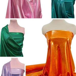 May include: Five different colors of metallic fabric, including pink, green, orange, purple, and gold. The fabric is draped over mannequins to show its texture and drape.