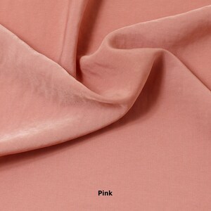 May include: A close-up of a pink fabric with soft folds and a silky sheen. The word "Pink" is printed in white at the bottom of the image. The fabric appears to be a lightweight material, possibly silk or satin.