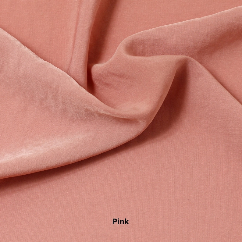 May include: A close-up of a pink fabric with soft folds and a silky sheen. The word "Pink" is printed in white at the bottom of the image. The fabric appears to be a lightweight material, possibly silk or satin.