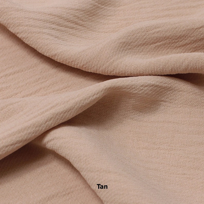 May include: Close-up of a tan fabric with a textured surface. The fabric is soft and drapes nicely.