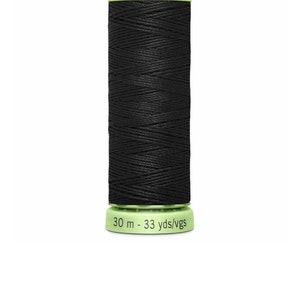 Może przedstawiać: Czarna szpula nici Gütermann Heavy-Duty/Top Stitch o długości 30 metrów (33 jardów). Szpula ma zieloną etykietę z nazwą marki i długością nici.