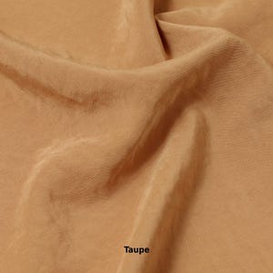 May include: Close-up of a folded piece of taupe-colored fabric. The fabric has a smooth, silky texture with subtle variations in tone, creating a soft, flowing appearance. The word "Taupe" is printed in black at the bottom of the image.