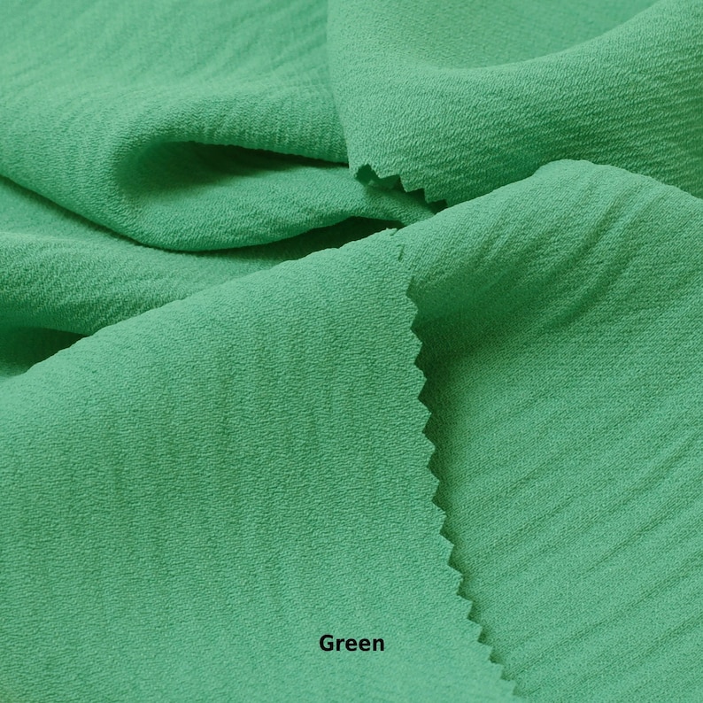 May include: Close-up of a green fabric with a textured surface. The fabric is folded in half, with the fold at the bottom of the image. The word "Green" is printed in white at the bottom of the image.