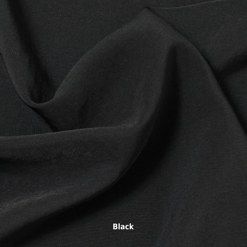 May include: A close-up shot of black fabric with soft folds and a smooth texture. The word "Black" is printed in white at the bottom of the image. The fabric appears to be lightweight and flowing.