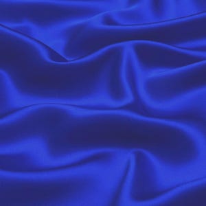 Puede incluir: Una tela suave de color azul real con pliegues suaves y fluidos. La tela tiene un brillo sedoso y una sensación lujosa.