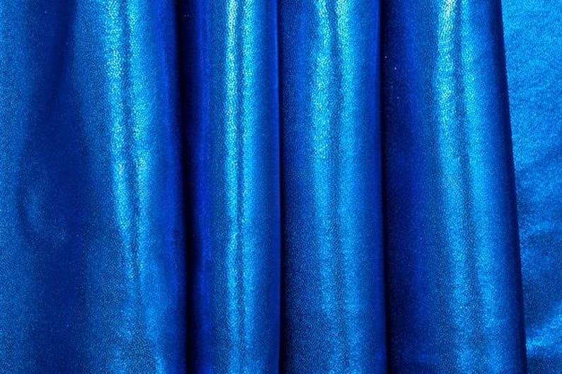 May include: Close-up of a blue metallic fabric with a smooth, shiny texture. The fabric is folded and draped, creating a soft, flowing effect.