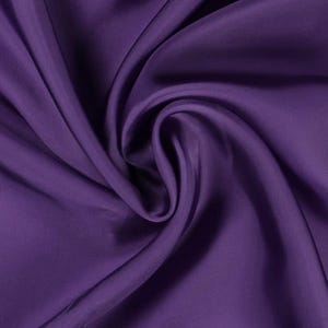 May include: Close-up of a deep purple fabric with a silky texture. The fabric is draped and folded, creating soft shadows and highlights. The color is a rich, saturated shade of purple.