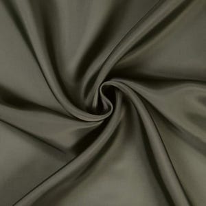 May include: Close-up of olive green fabric with soft folds and a swirling pattern. The fabric has a subtle sheen, creating highlights and shadows. The material appears smooth and luxurious, suitable for apparel or home decor.