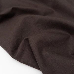 Puede incluir: Primer plano de una tela marr&oacute;n oscuro con textura y pliegues visibles. El material parece ser un textil tejido, posiblemente lino o algod&oacute;n, con un acabado mate. El color es un tono profundo y terroso.