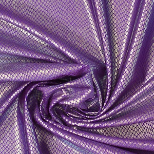 Op de afbeelding: Close-up van een glanzende, getextureerde stof met een reptielschubbenpatroon. De stof is dieppaars met zilveren accenten, wat een glinsterend effect creëert. Het materiaal is gedrapeerd en gevouwen.