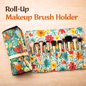 May include: A roll-up makeup brush holder with a colorful floral pattern. The holder is open, displaying various makeup brushes. The text "Roll-Up Makeup Brush Holder" is in orange. The holder is made of fabric and has a tie closure.