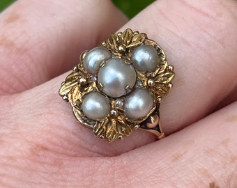 May include: A gold ring with a cluster of six pearls set in a floral design.