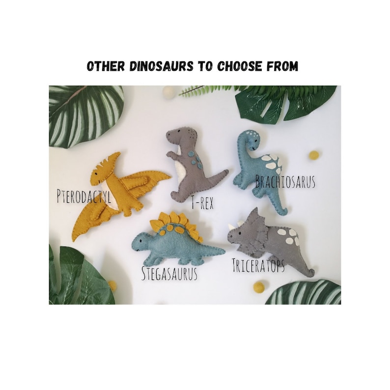 Pode incluir: Brinquedos de dinossauro de feltro em v&aacute;rias cores, incluindo cinza, azul e amarelo. Os dinossauros est&atilde;o dispostos em um fundo verde frondoso. Os nomes dos dinossauros est&atilde;o escritos abaixo de cada brinquedo: Pterod&aacute;ctilo, T-Rex, Braquiossauro, Estegossauro e Tricer&aacute;tops.