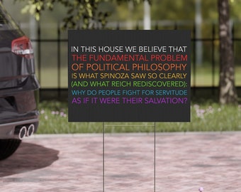 May include: Black yard sign with white text that reads "In this house we believe that the fundamental problem of political philosophy is what Spinoza saw so clearly (and what Reich rediscovered): Why do people fight for servitude as if it were their salvation?"