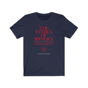 May include: A navy blue t-shirt with red text that reads "THE ETHICS OF SPINOZA" and "A TYPOLOGY OF IMMANENT MODES OF EXISTENCE" with a small red symbol and the text "By BARUCH SPINOZA" underneath.