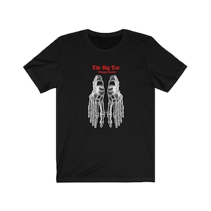 May include: Black t-shirt with a white illustration of two skeletal feet. The text "The Big Toe" and "Georges Bataille" is printed in red.