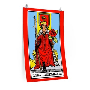 May include: A tarot card with a red background and a yellow border. The card depicts a woman wearing a red robe and a crown, holding a staff and a red rose. The card is titled "ROSA LUXEMBURG".