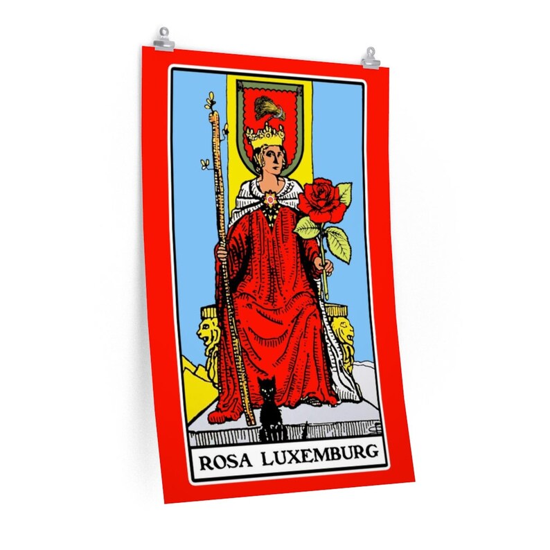 May include: A tarot card with a red background and a yellow border. The card depicts a woman wearing a red robe and a crown, holding a staff and a red rose. The card is titled "ROSA LUXEMBURG".