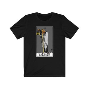 K&ouml;nnte beinhalten: Schwarzes T-Shirt mit einem Grafikdruck der IX Karte aus dem Rider-Waite Tarot Deck. Die Karte zeigt einen Mann, der eine Laterne h&auml;lt und mit einem Stab geht. Der Text "DELEUZE" ist unter der Karte gedruckt.