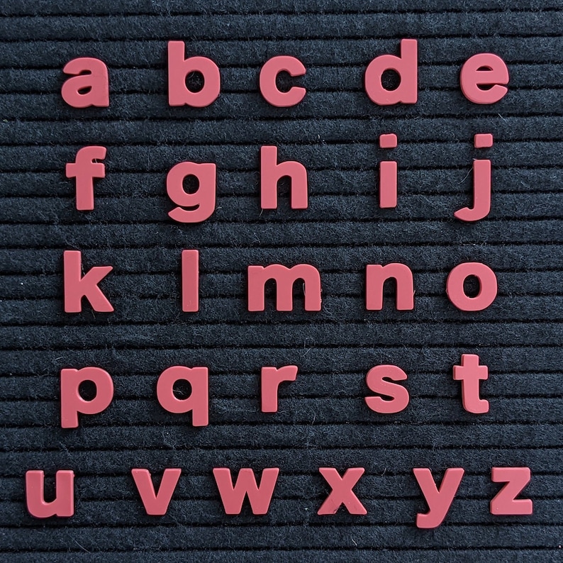 May include: A black felt letter board with the alphabet in red plastic letters. The letters are arranged in rows, starting with "a" and ending with "z".