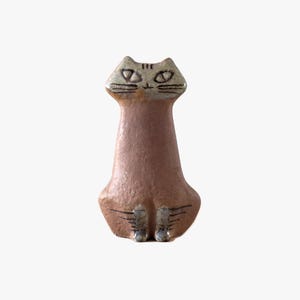 May include: A brown and grey ceramic cat figurine. The cat has a long neck and is in a seated position. The figurine has detailed facial features and is a decorative item for the home.