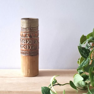May include: A cylindrical ceramic vase with a light brown base and a textured, patterned midsection. The upper portion is a darker brown with a beige rim. The vase features geometric and linear designs. A decorative piece for the home.