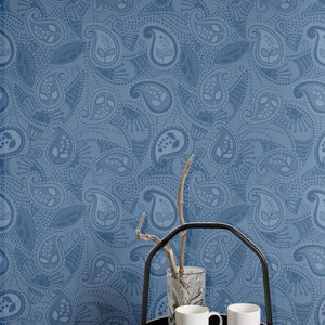 May include: A blue paisley patterned wallpaper with a black metal serving tray with two white ceramic mugs and a clear glass vase with a twig inside.
