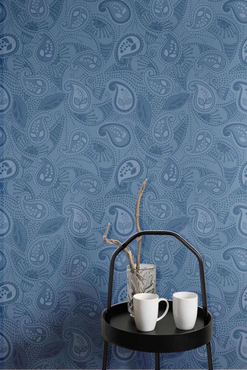 May include: A blue paisley patterned wallpaper with a black metal serving tray with two white ceramic mugs and a clear glass vase with a twig inside.