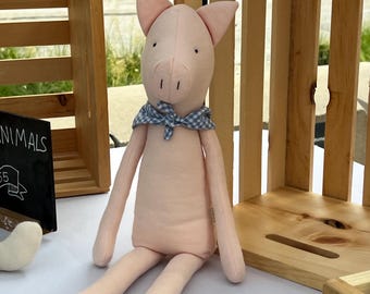 May include: A light pink fabric pig stuffed animal with long limbs and pointed ears. The pig features simple black embroidered eyes and nostrils, and it is wearing a small blue and white gingham patterned fabric neckerchief tied in a knot.