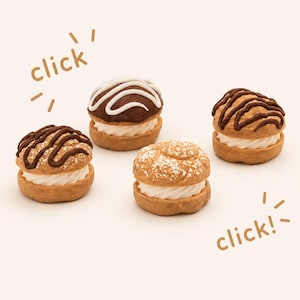 May include: Four cream puff pastries with light brown shells and white cream centers. Two are drizzled with dark brown icing, one has white icing over dark brown, and one is dusted with white powder. The text "click" appears twice in brown.