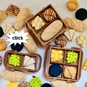 Pode incluir: Uma vista aérea mostra alimentos em miniatura, incluindo pão, queijo, uvas e biscoitos, dispostos em pequenas cestas de piquenique. A palavra "click" está em uma estrela branca.
