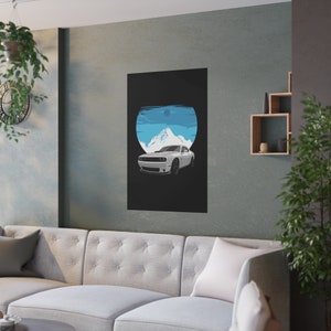 Modern living room with a sleek gray wall featuring a custom car art poster of a white muscle car against a blue mountain backdrop. A tufted sofa with soft cushions, minimalist shelving, and greenery complete the stylish, cozy space