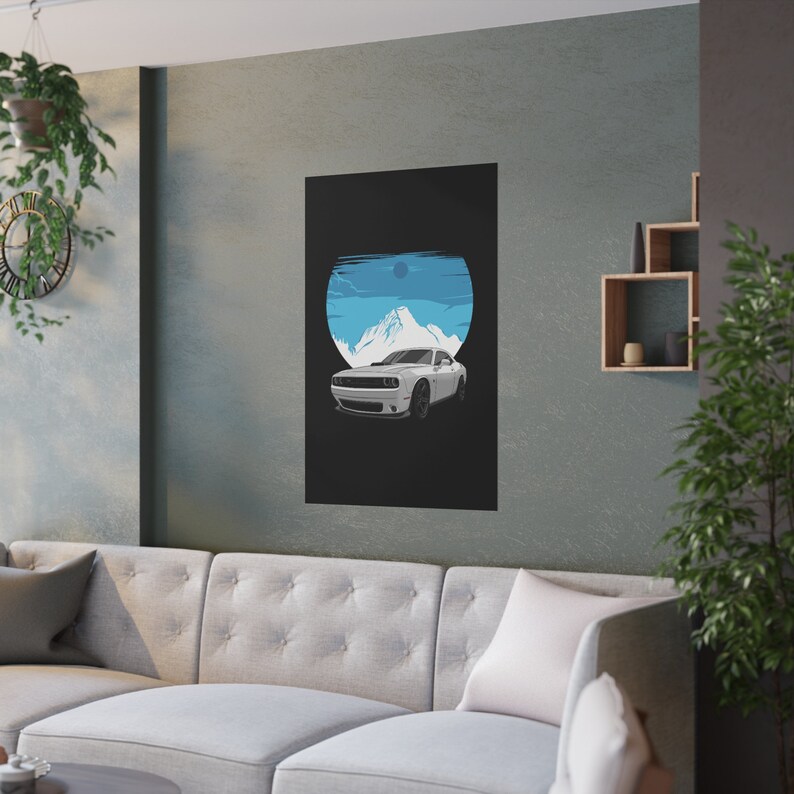 Modern living room with a sleek gray wall featuring a custom car art poster of a white muscle car against a blue mountain backdrop. A tufted sofa with soft cushions, minimalist shelving, and greenery complete the stylish, cozy space