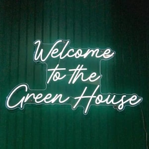 May include: White neon sign with the text "Welcome to the Green House" on a dark green wall.
