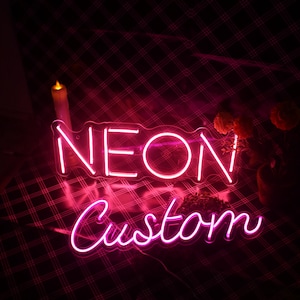 以下が含まれることがあります： 「NEON CUSTOM」という文字が書かれたピンクのネオンサイン。筆記体で書かれています。