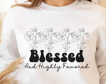 May include: White sweatshirt with a black graphic design featuring a line drawing of flowers and the text "Blessed And Highly Favored".