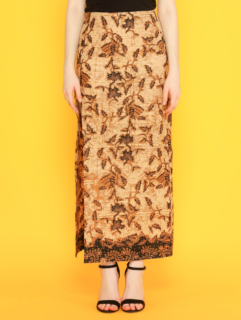 May include: A long brown skirt with a black floral pattern. The skirt has a slit on the side and a black waistband.