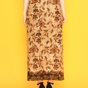 May include: A long brown skirt with a black floral pattern. The skirt has a fitted waist and a flowing hem. The skirt is made of a lightweight fabric and is perfect for warm weather.