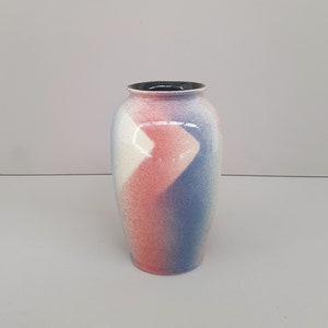 May include: A ceramic vase with a white, pink, and blue abstract design. The vase has a round body and a narrow opening.