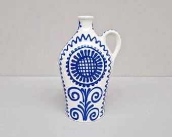 Könnte beinhalten: Eine weiße Keramikkanne mit blauem Blumendesign. Die Kanne hat einen Henkel und einen schmalen Hals.